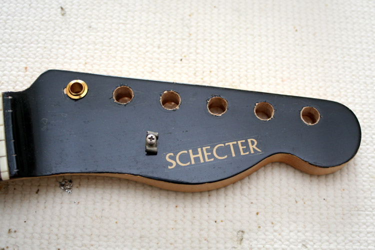 The face plate is black on this old Schecter neck. The plastic nut and the silver butterfly stringholder do not seem to be original and must be replaced with brass parts (which I don't have yet). One problem are the tuner holes which are too big for Kluson-style tuners (they are correct for Schaller tuners)